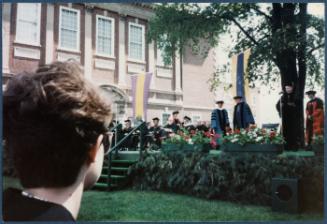 Eugénie Prendergast receiving her honorary degree at 1985 Williams College Commencement ceremony including friends and college officials; Eugénie Prendergast on stage in front of microphone