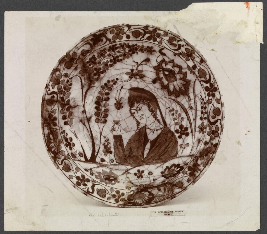 Oriental Plate with female figure holding small cup surrounded by floral design.