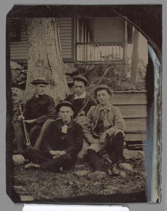 Portrait of four men sitting in front of a house