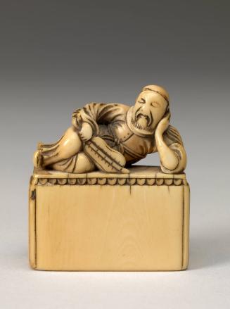 Netsuke depicting a reclining man on pedestal/bed