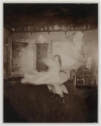 Loïe Fuller practicing at home in front of a Mucha playbill, Passy near Paris