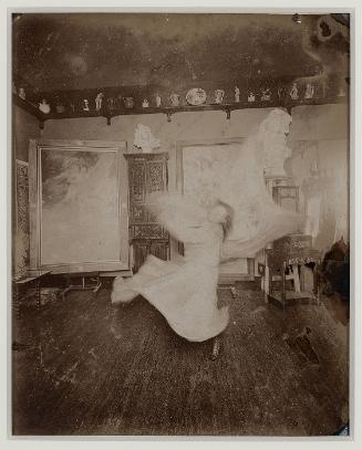 Loïe Fuller practicing at home in front of a Mucha playbill, Passy near Paris
